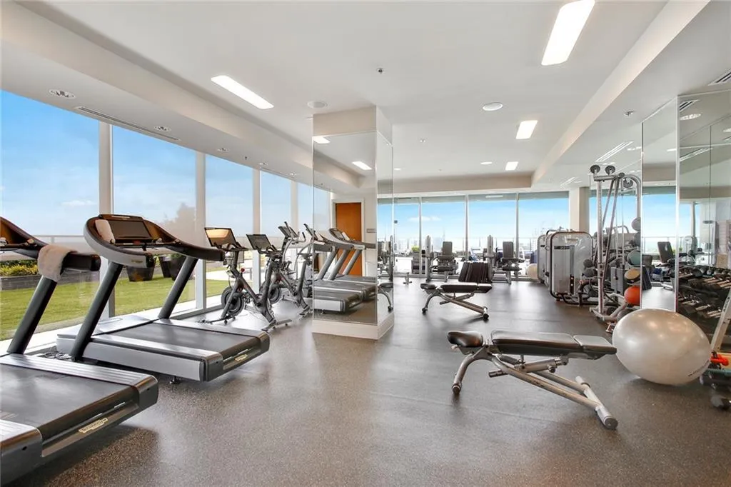 Gym with expansive windows, a raised ceiling, and recessed lighting
