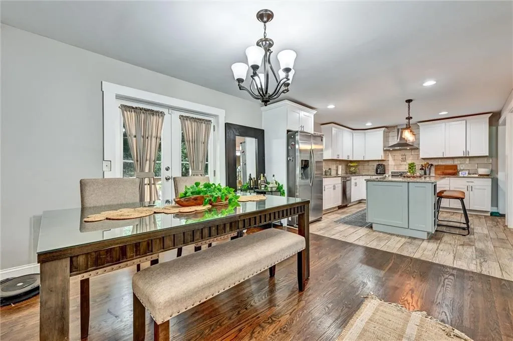 Dining space with light wood-type flooring, french doors, and an inviting chandelier