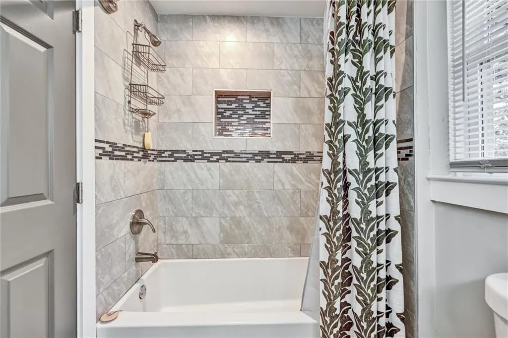 Bathroom featuring toilet and shower / bathtub combination with curtain
