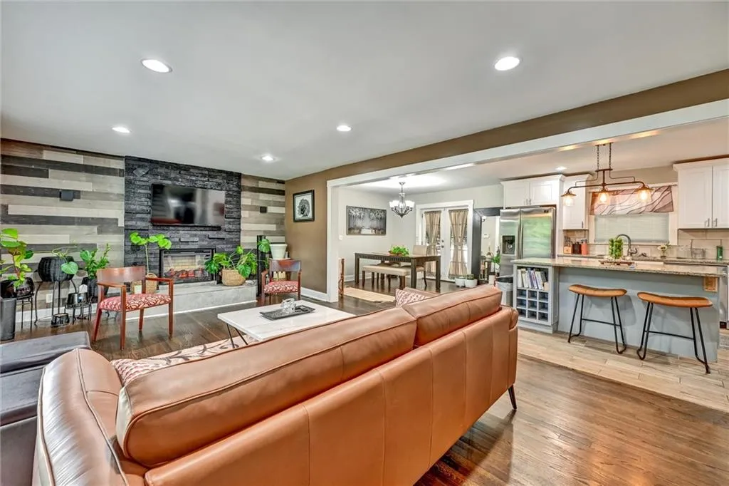 Living room featuring light wood-type flooring, a tiled fireplace, sink, and a chandelier