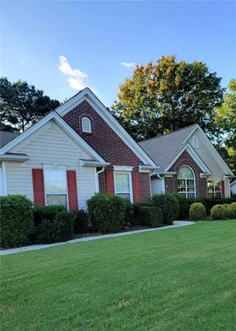 Brick and siding exterior with gabled rooflines, arched window, decorative shutters, and manicured shrubbery