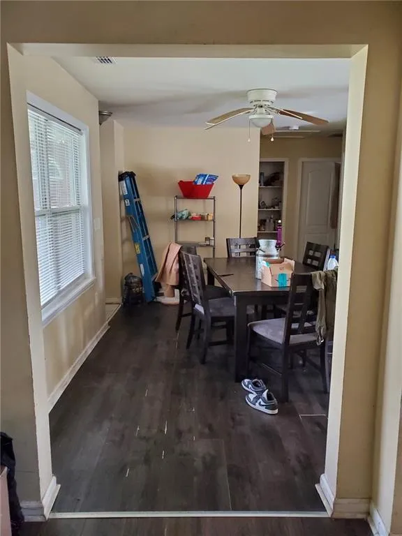 Dining space featuring built in shelves, baseboards, a ceiling fan, and wood finished floors