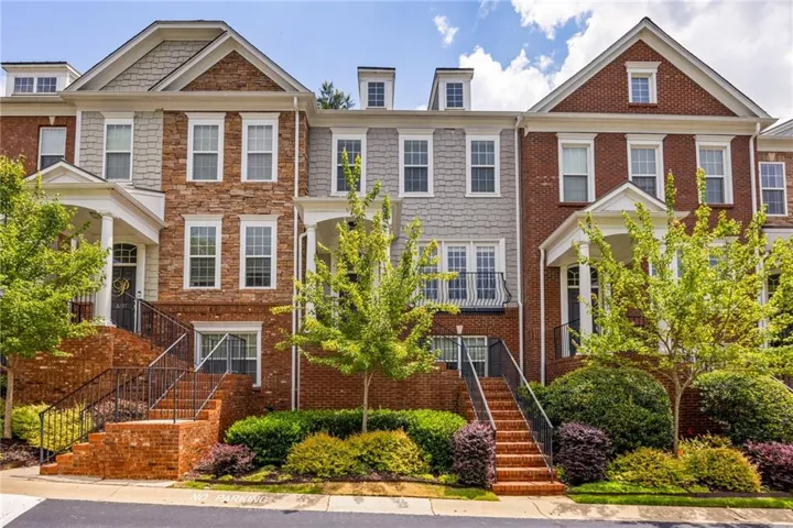 Brick and stone exterior with dormer windows, covered entryways, and mature landscaping