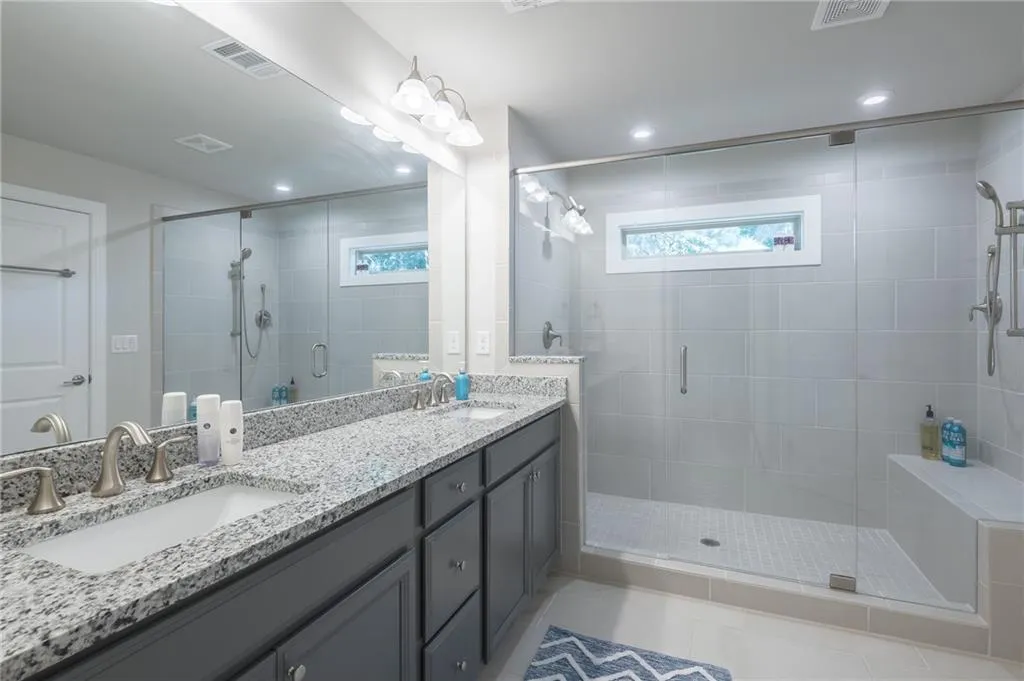 Bathroom featuring double vanity, a shower stall, plenty of natural light, and recessed lighting