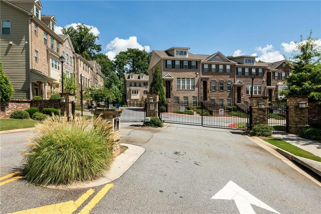 View of asphalt road with a residential view, a gate, and curbs
