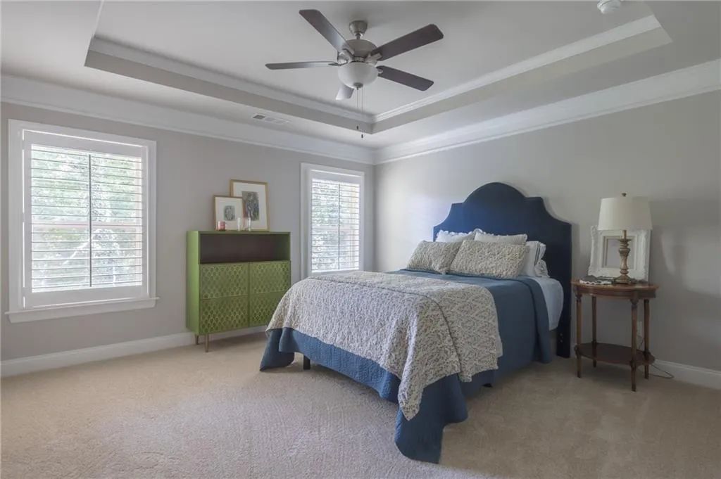 Bedroom with a raised ceiling, carpet, ornamental molding, and a ceiling fan