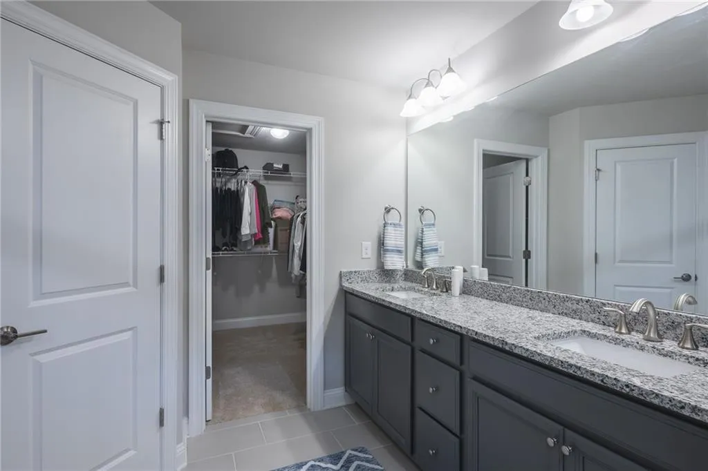 Full bath featuring double vanity, a spacious closet, and tile patterned floors