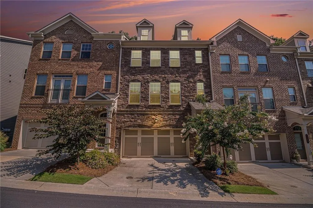 View of front of property featuring driveway, an attached garage, and brick siding