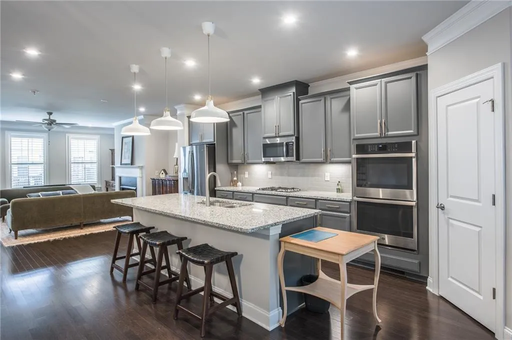 Kitchen with gray cabinets, appliances with stainless steel finishes, a center island with sink, open floor plan, and recessed lighting
