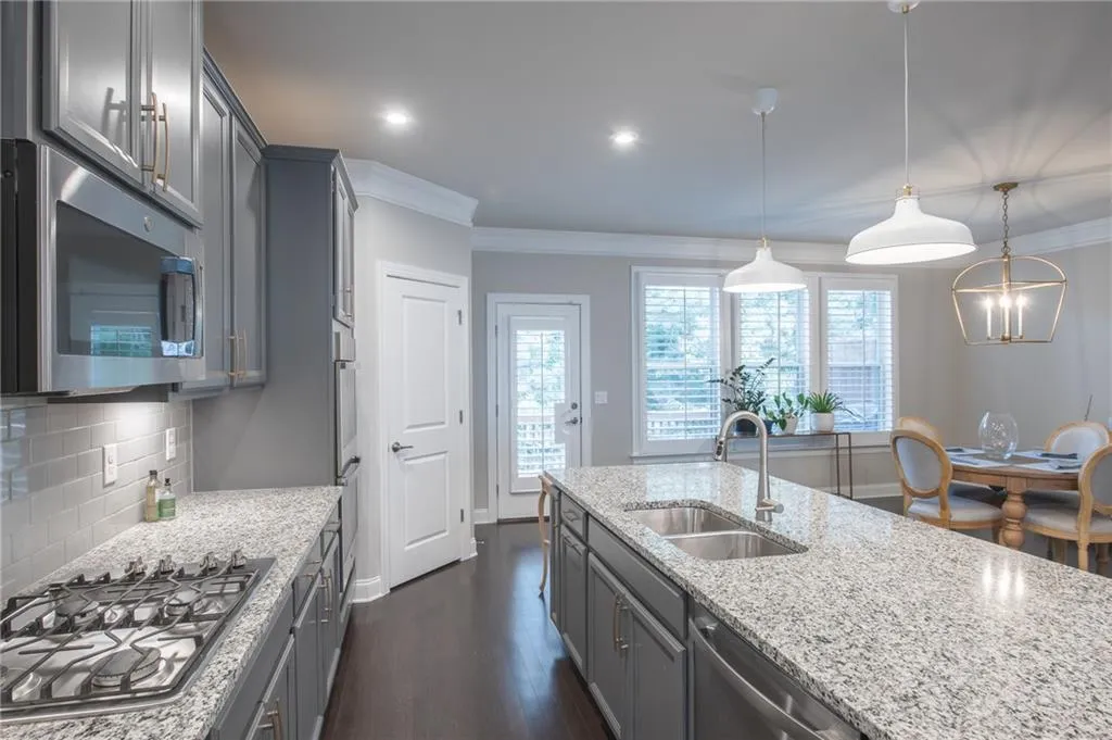 Kitchen with stainless steel appliances, crown molding, light stone countertops, dark wood finished floors, and backsplash