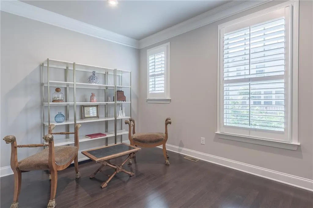 Sitting room featuring plenty of natural light, dark wood-style floors, and ornamental molding
