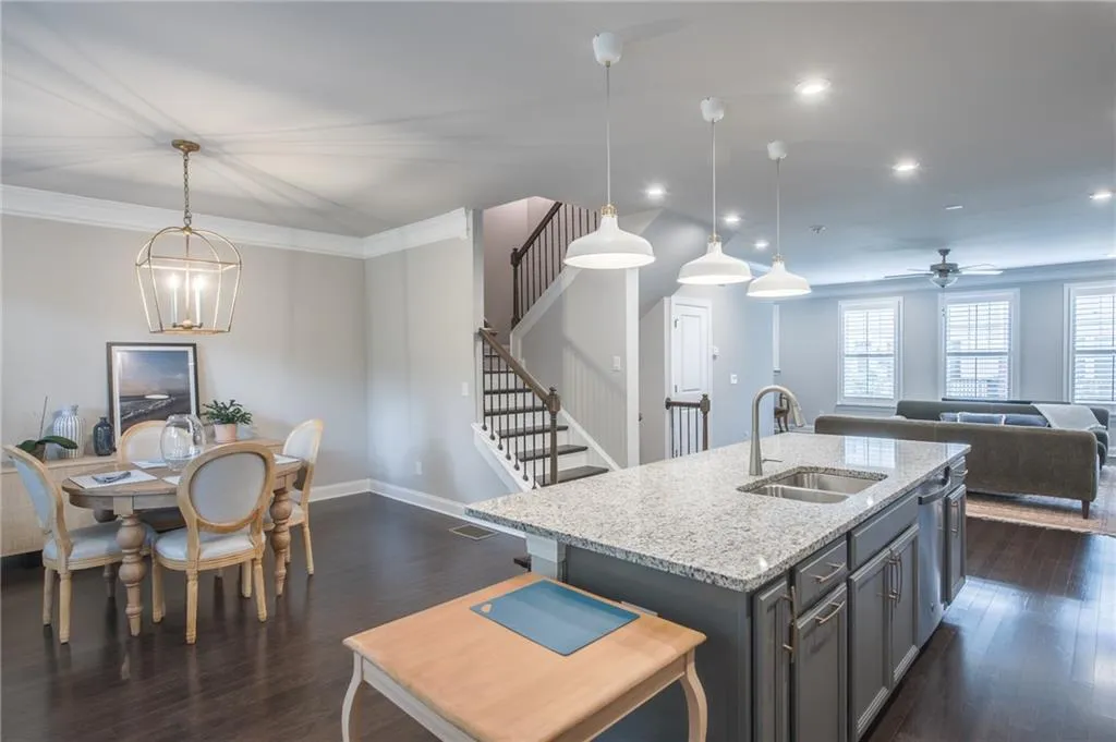 Kitchen featuring open floor plan, dark wood-style flooring, light stone countertops, recessed lighting, and pendant lighting