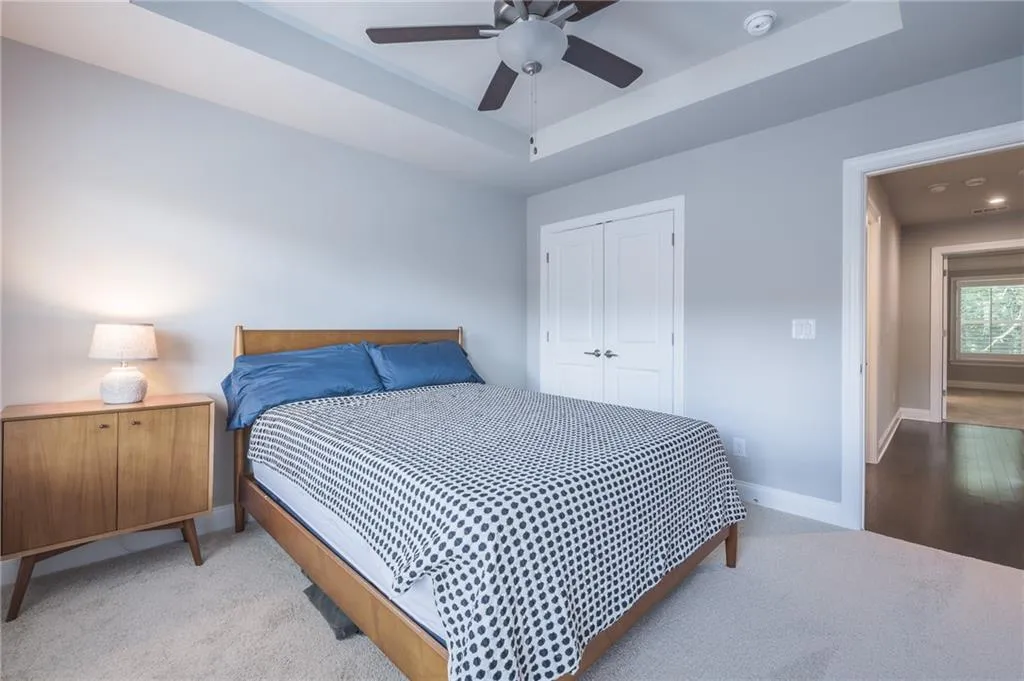 Carpeted bedroom featuring a closet, ceiling fan, and a tray ceiling