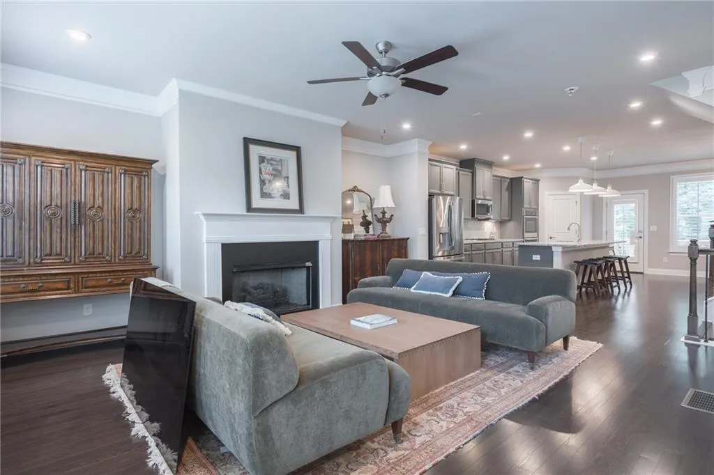 Living area with a ceiling fan, ornamental molding, a fireplace, recessed lighting, and dark wood-style floors