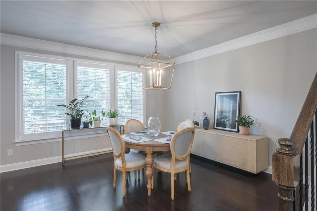 Dining space featuring a chandelier, healthy amount of natural light, dark wood finished floors, and crown molding