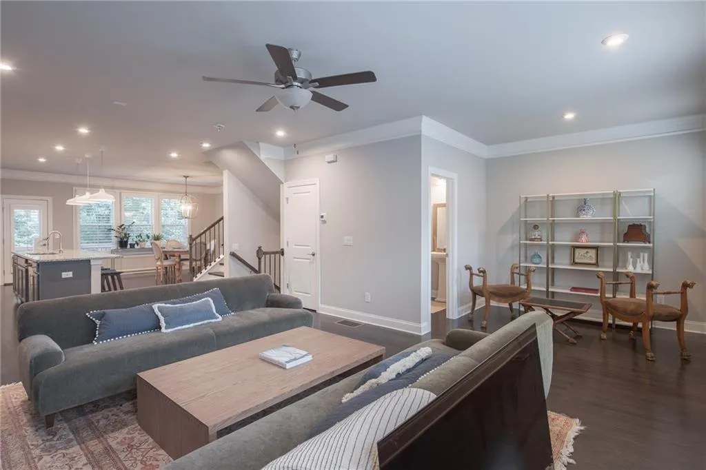 Living area with crown molding, recessed lighting, dark wood-style flooring, stairway, and ceiling fan