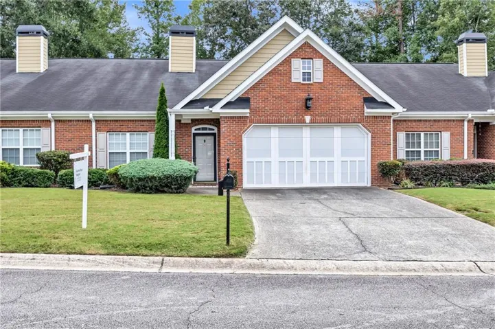 Brick exterior with white garage door, gabled roofline, and front lawn