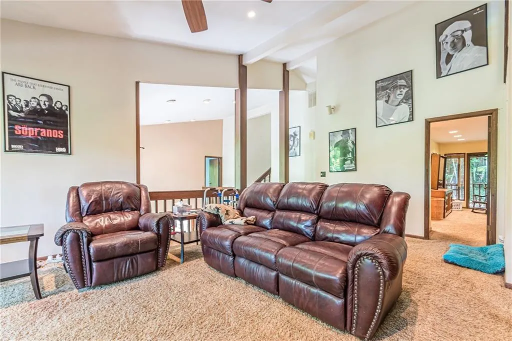 Carpeted living room with lofted ceiling with beams and ceiling fan