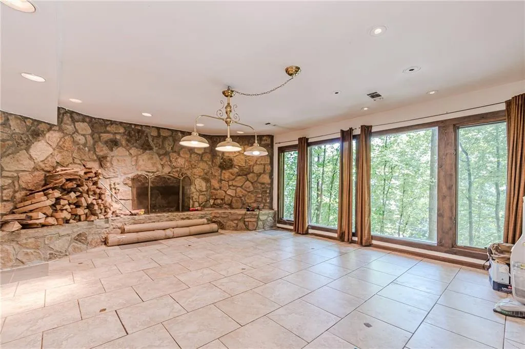 Unfurnished living room with light tile patterned flooring, a healthy amount of sunlight, and a stone fireplace