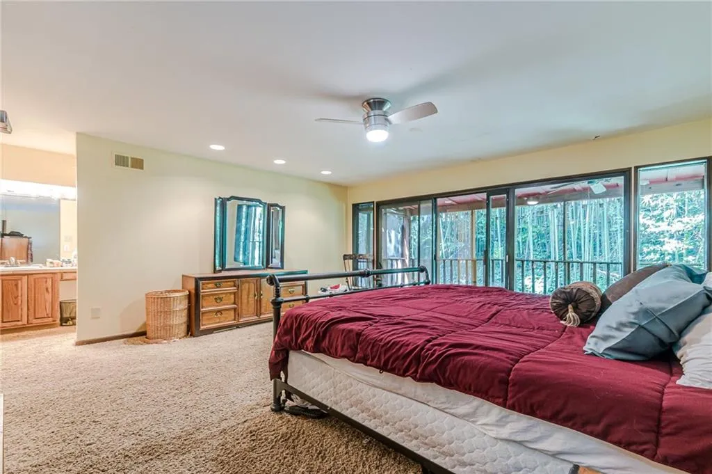 Carpeted bedroom with ceiling fan and connected bathroom
