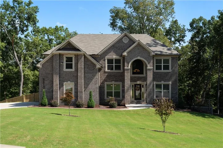Two-story brick exterior with a gabled roofline, arched entry, and a prominent front lawn