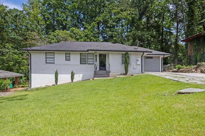 Single story home with roof with shingles, a front lawn, concrete driveway, and a garage