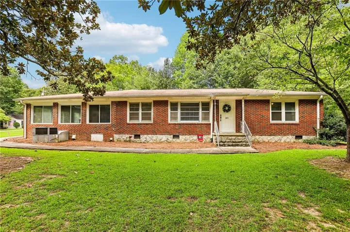 Brick ranch-style residence featuring a prominent front entrance with stone steps and metal railings