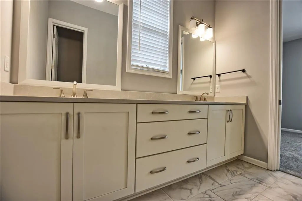 Bathroom with double vanity, a sink, marble finish floor, and baseboards