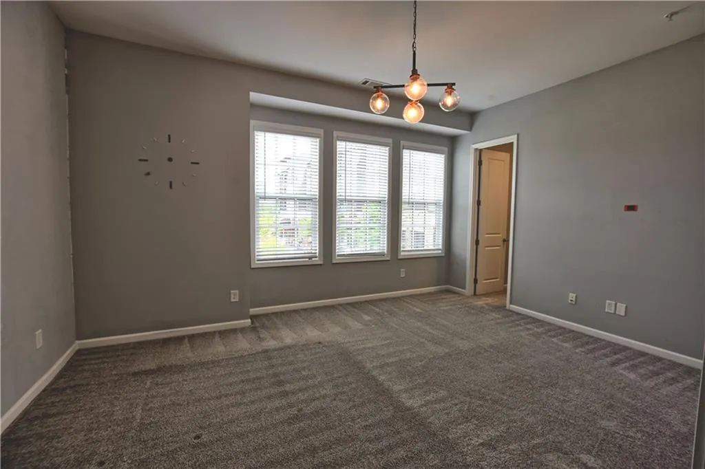 Empty room with visible vents, baseboards, an inviting chandelier, and carpet