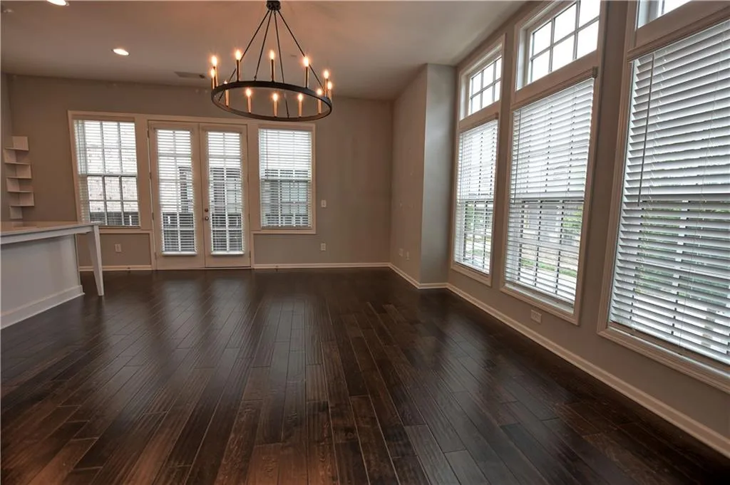 Unfurnished dining area with baseboards, dark wood-style flooring, and a notable chandelier