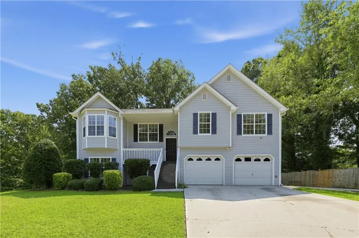 Light gray siding exterior with a bay window, a front entry deck, a two-car garage, and a concrete driveway
