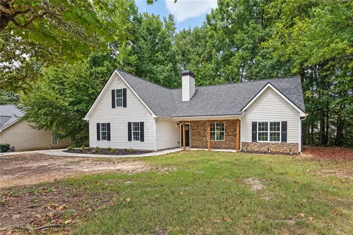 White siding exterior with a dark shingle roof, stone accenting, and a covered entry
