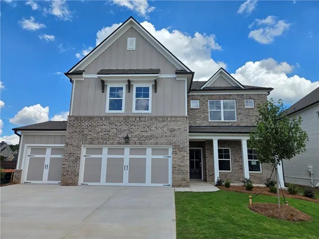 Brick and siding exterior with a multi-car garage, covered entry, and manicured landscaping