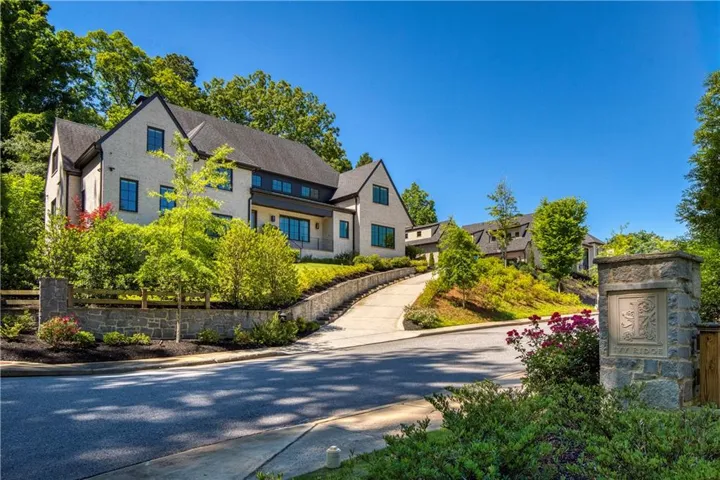Contemporary residence featuring a stucco exterior, dark roof, dark-framed windows, and a stone retaining wall