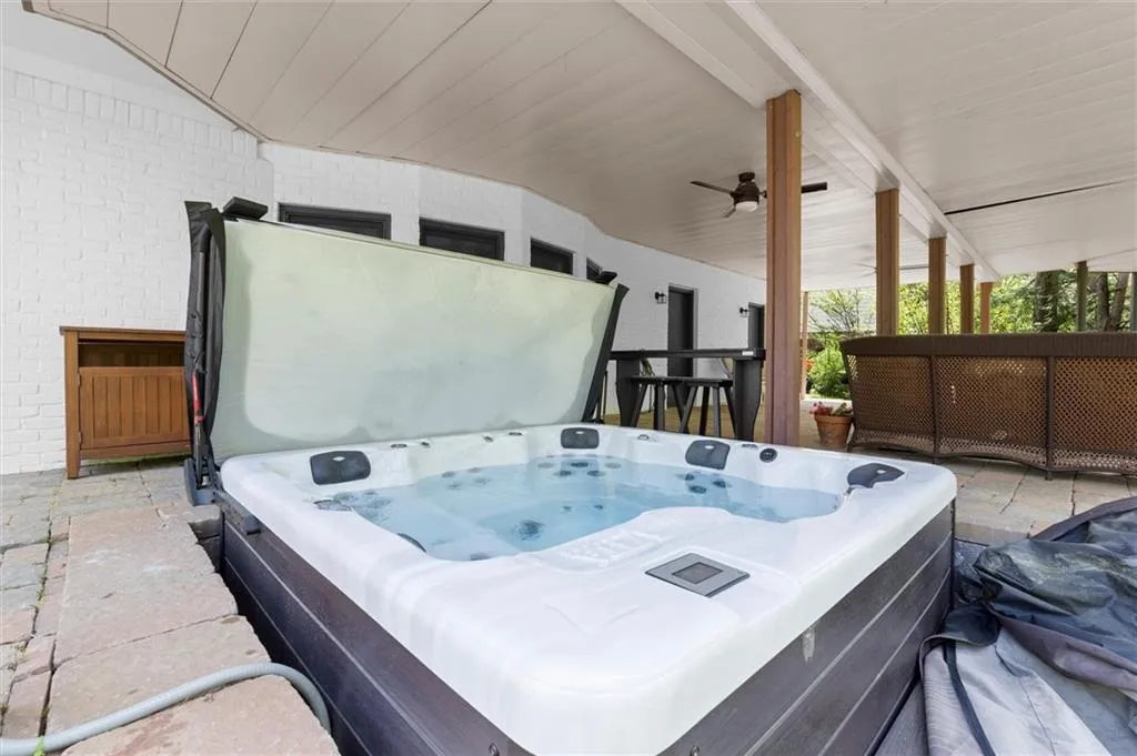 Covered stone patio with a built-in hot tub and under-deck drainage system