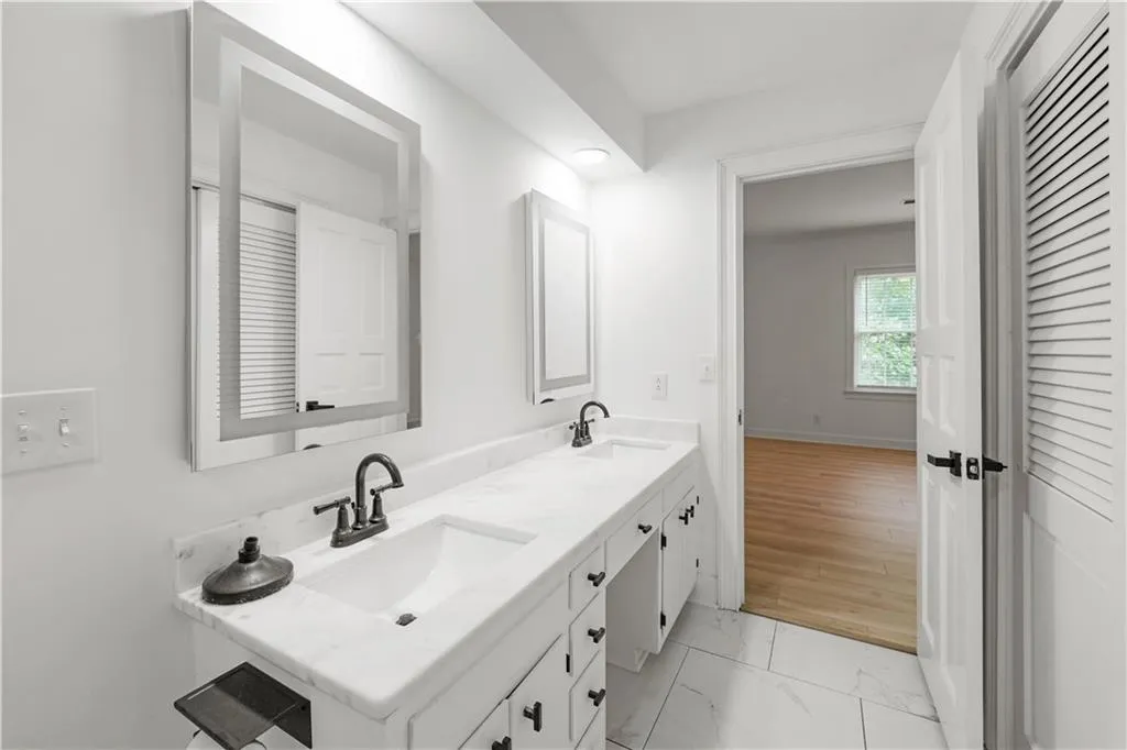 Full bathroom featuring double vanity and light marble finish flooring
