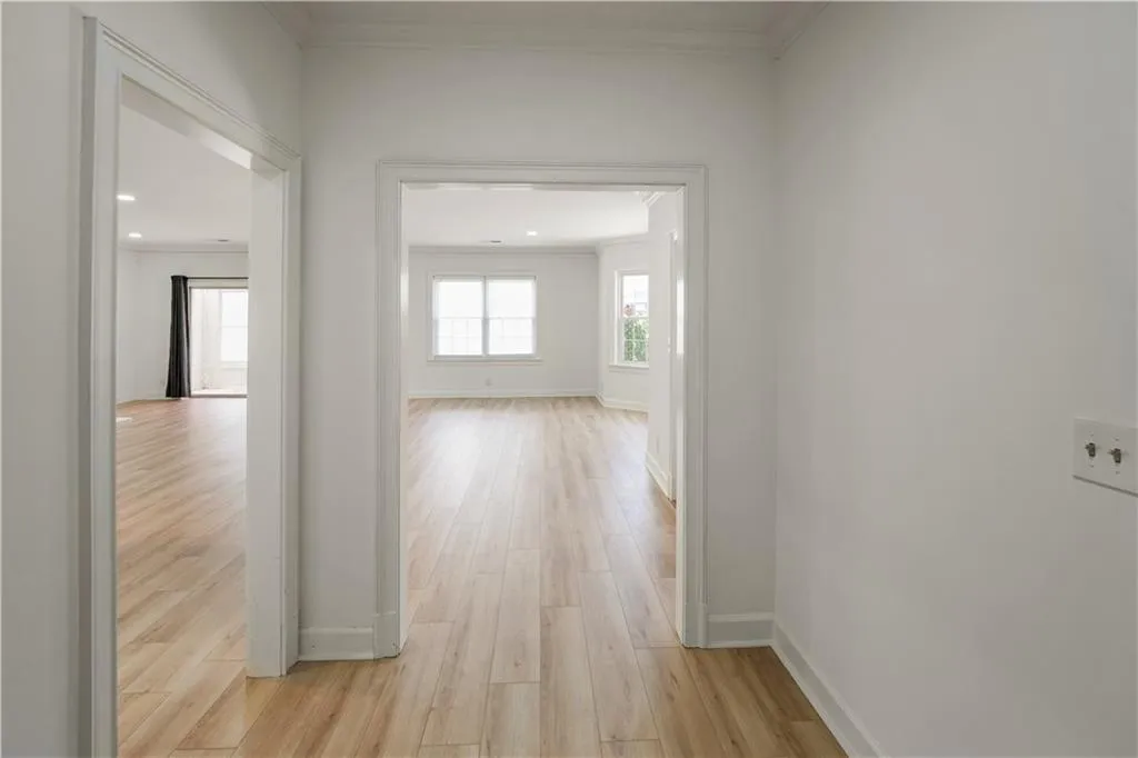 Hallway featuring light wood finished floors and crown molding