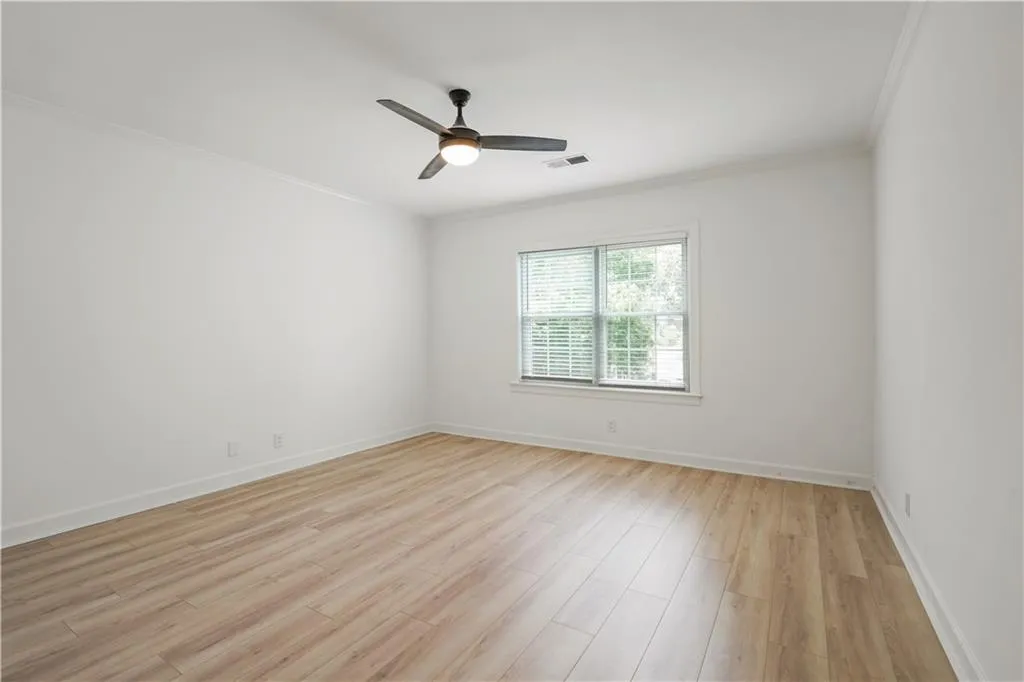 Spare room featuring ornamental molding, light wood finished floors, and ceiling fan