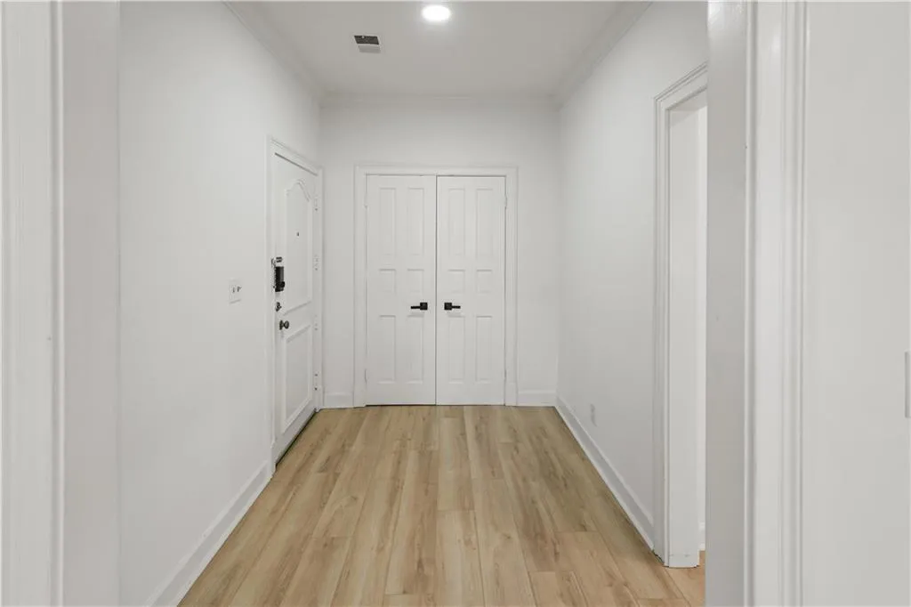 Hallway featuring light wood-style flooring, ornamental molding, and recessed lighting