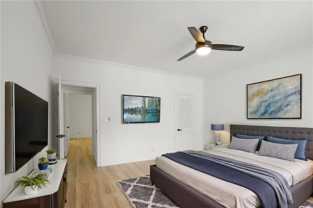 Bedroom with ornamental molding, light wood-type flooring, and a ceiling fan