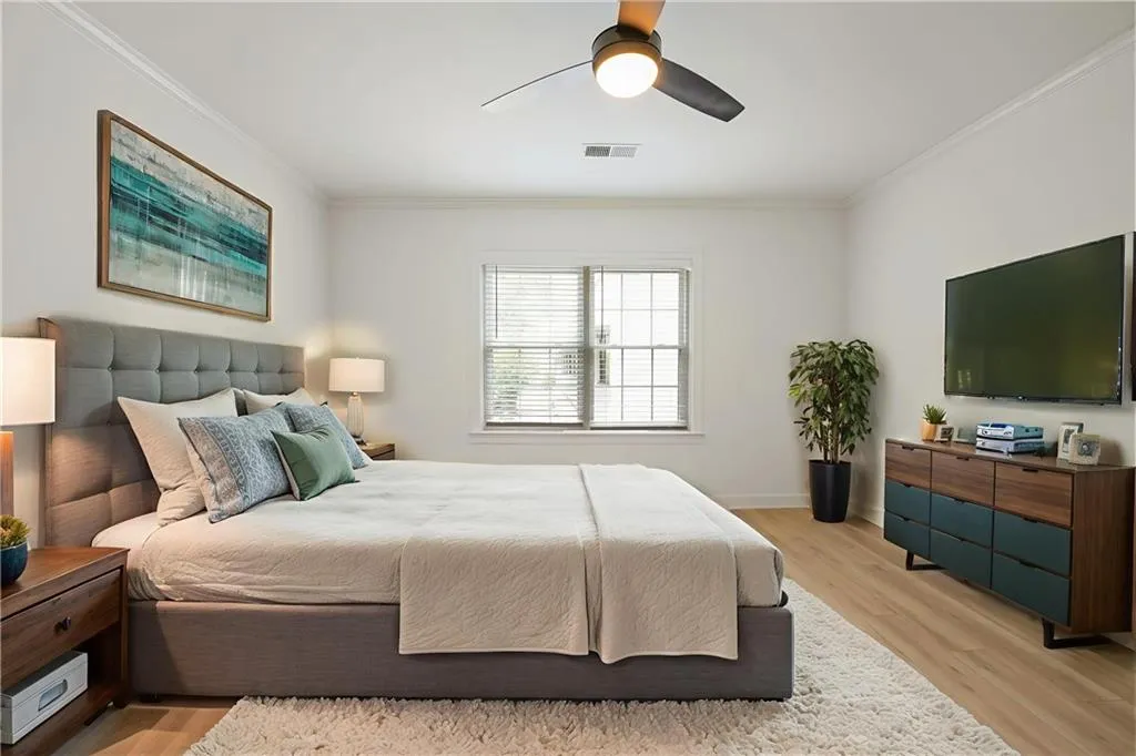 Bedroom featuring light wood-style flooring, ornamental molding, and ceiling fan