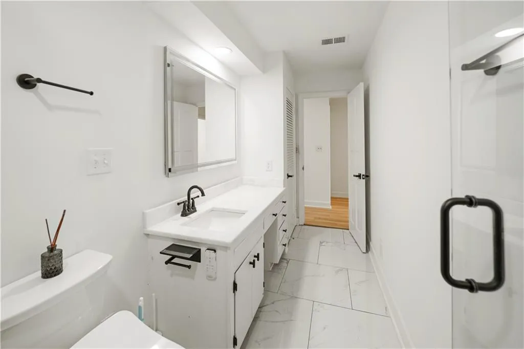 Bathroom featuring vanity, light marble finish flooring, and recessed lighting