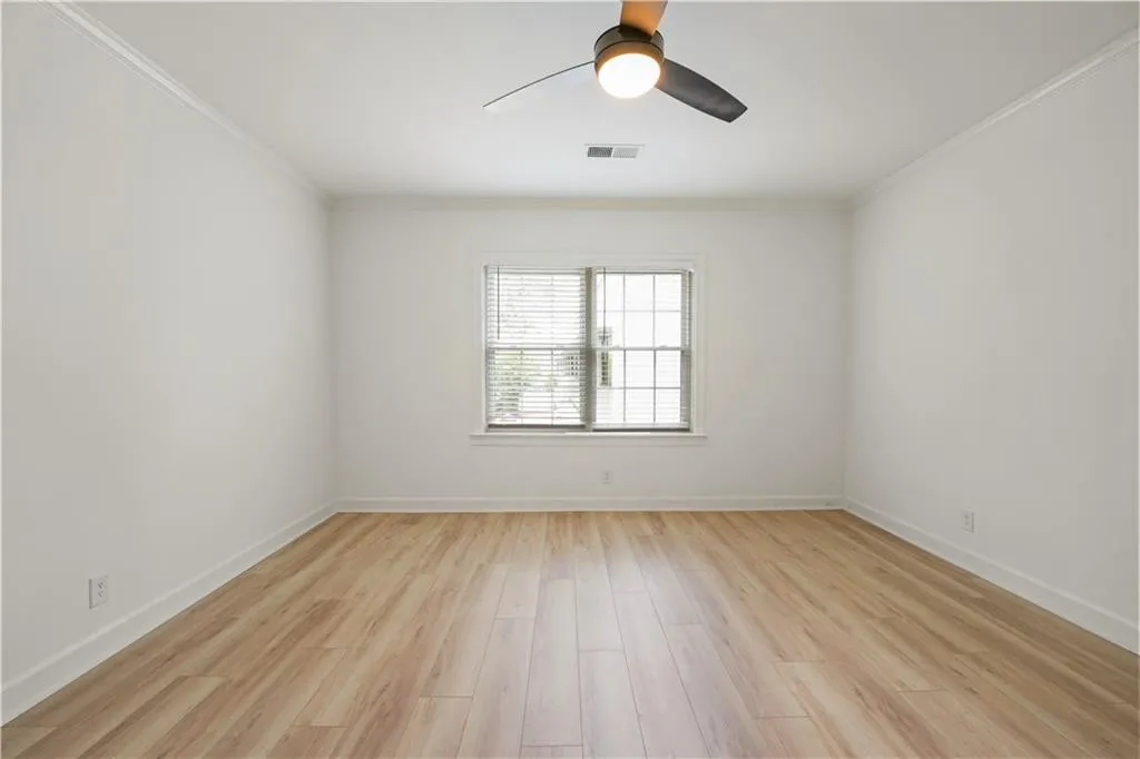 Spare room featuring light wood-style flooring, ceiling fan, and ornamental molding