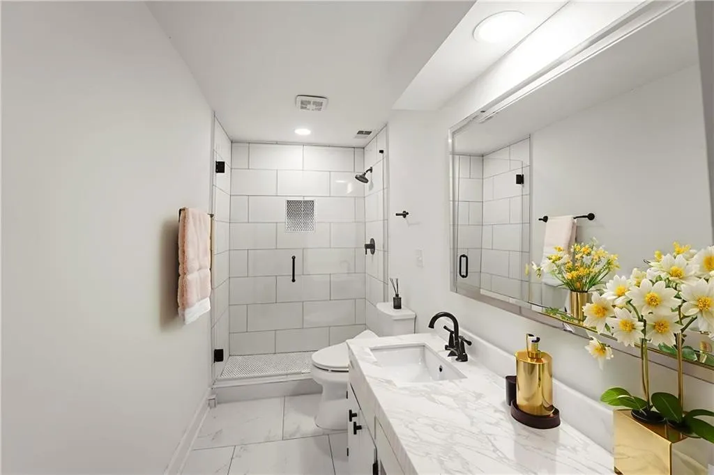 Full bath featuring vanity, a shower stall, marble look tiles, and recessed lighting