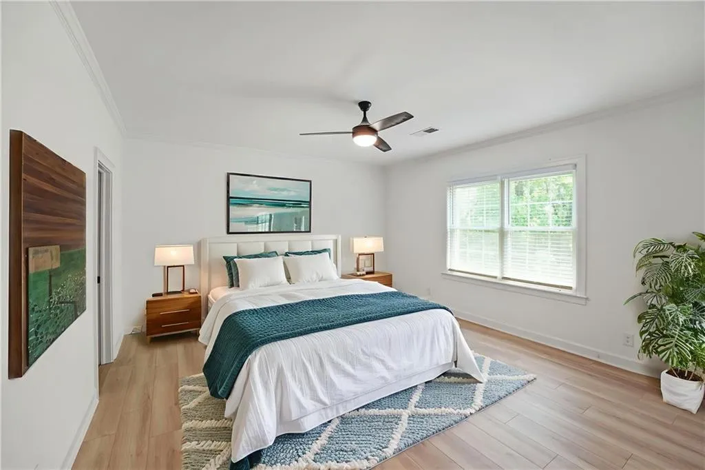 Bedroom with crown molding, light wood-type flooring, and ceiling fan