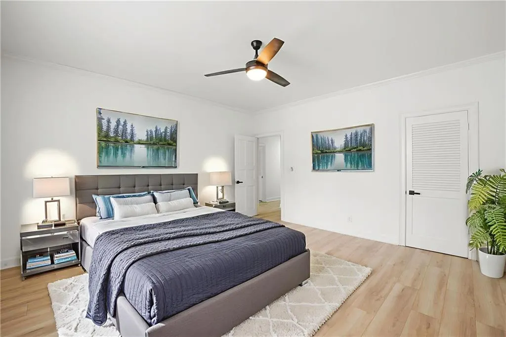Bedroom with ornamental molding, light wood-type flooring, and a ceiling fan