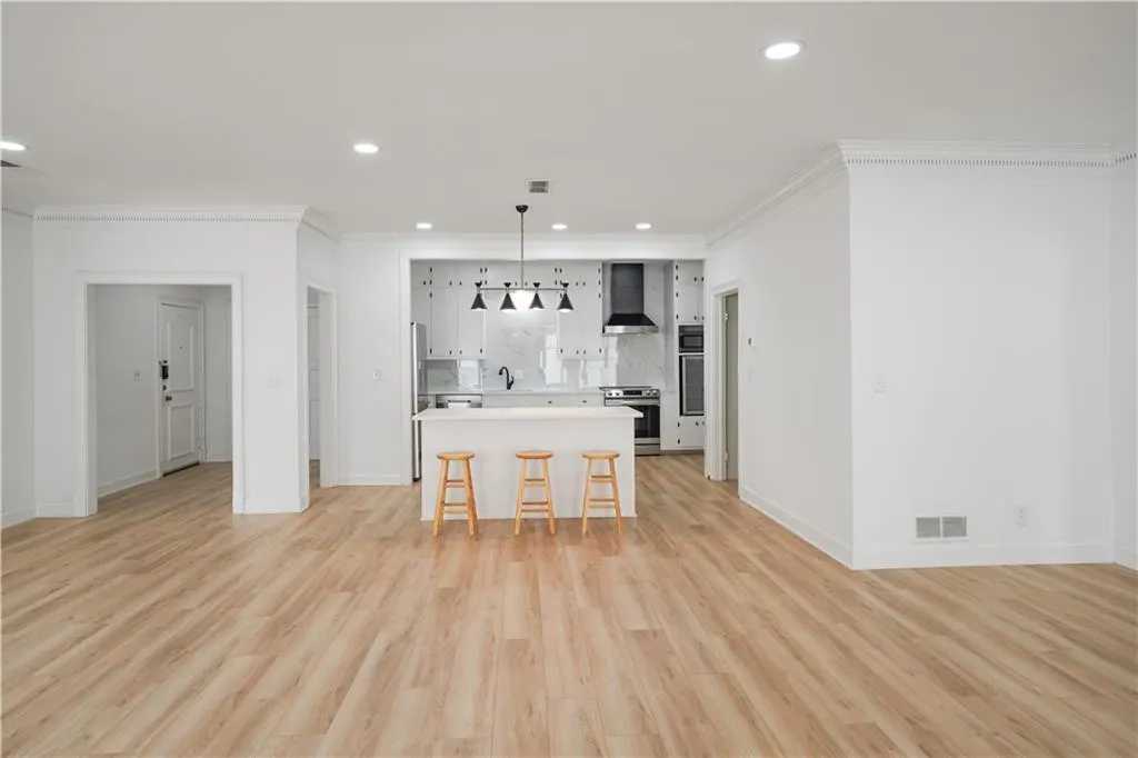 Kitchen with a kitchen island, crown molding, a kitchen bar, light countertops, and hanging light fixtures