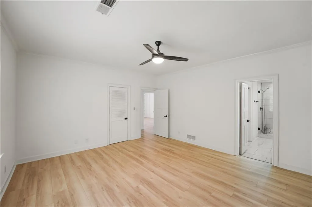 Unfurnished bedroom with crown molding, light wood-type flooring, ceiling fan, a closet, and ensuite bath