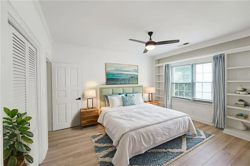 Bedroom featuring ornamental molding, light wood-style floors, and a ceiling fan