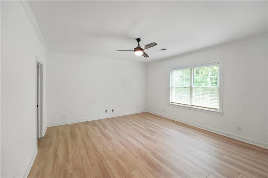 Unfurnished room with crown molding, light wood-type flooring, and a ceiling fan